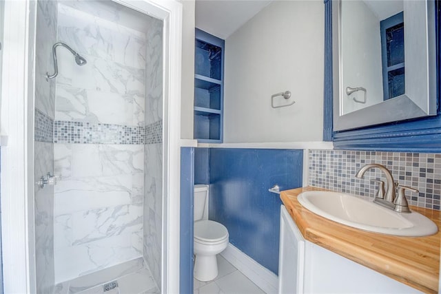 bathroom with tiled shower, vanity, toilet, and tile walls