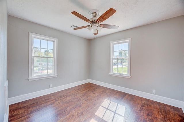 unfurnished room featuring a wealth of natural light, ceiling fan, dark wood-type flooring, and a textured ceiling