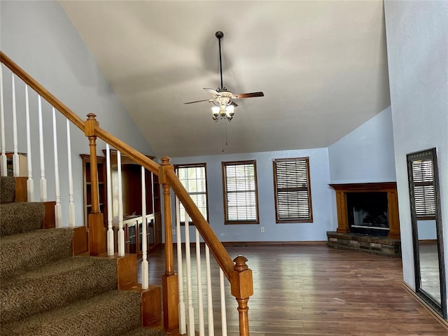 stairs with hardwood / wood-style floors, ceiling fan, a fireplace, and high vaulted ceiling