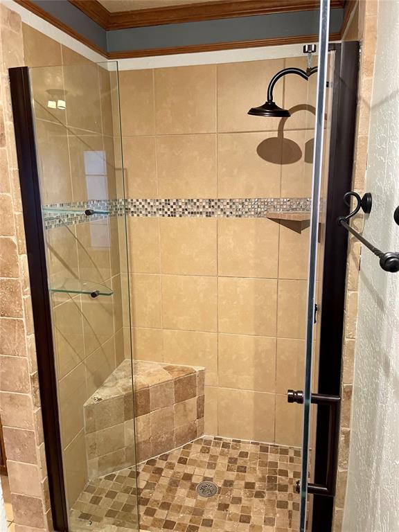 bathroom with an enclosed shower and crown molding