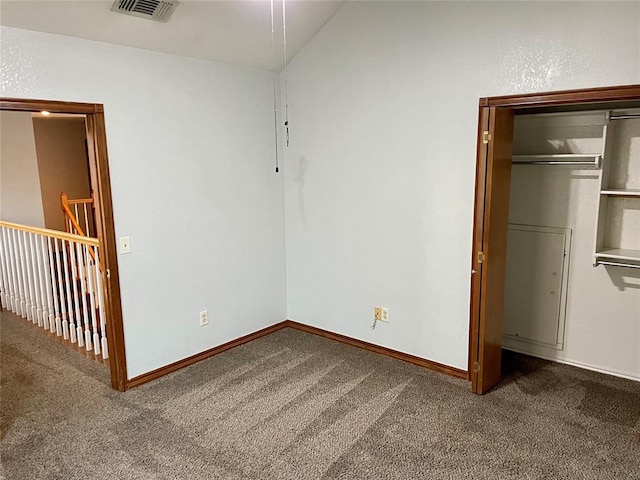 unfurnished bedroom with lofted ceiling, dark carpet, and a closet