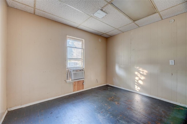 spare room with a paneled ceiling, wooden walls, cooling unit, and dark wood-type flooring