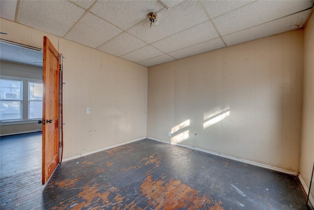 unfurnished room featuring wood walls, a drop ceiling, and dark hardwood / wood-style floors