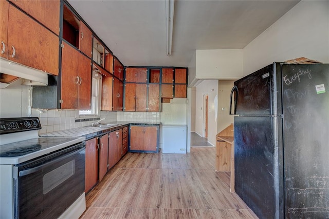 kitchen with backsplash, black fridge, sink, electric range, and light wood-type flooring