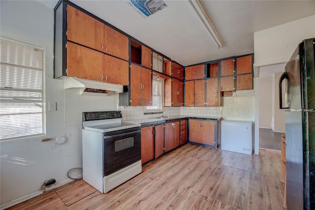 kitchen with black refrigerator, tasteful backsplash, white electric stove, and light hardwood / wood-style flooring