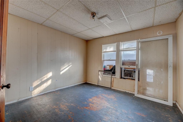 empty room with a drop ceiling, cooling unit, and wooden walls