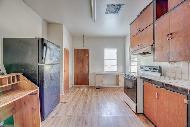 kitchen featuring backsplash, electric stove, black fridge, and light hardwood / wood-style floors