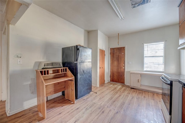 kitchen featuring stainless steel electric stove, black fridge, and light wood-type flooring