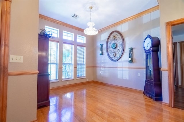 unfurnished dining area featuring an inviting chandelier, light hardwood / wood-style floors, and ornamental molding