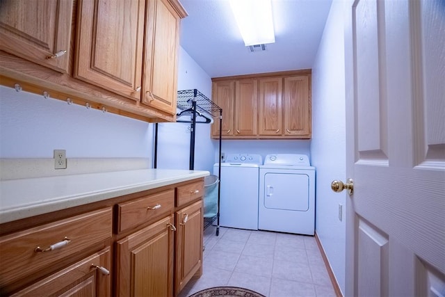 laundry room featuring washing machine and dryer, light tile patterned floors, and cabinets