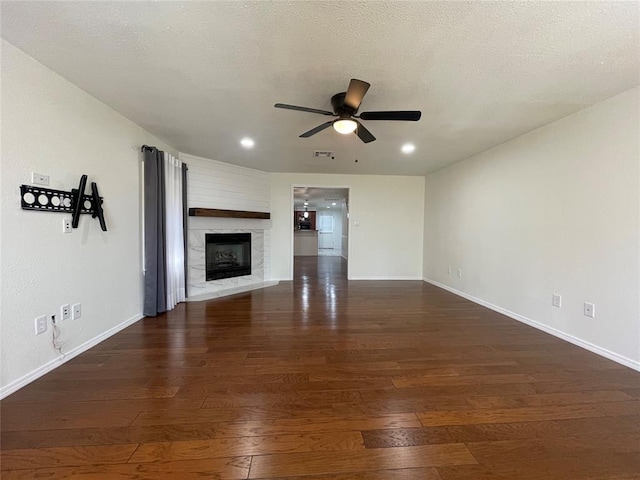 unfurnished living room featuring ceiling fan, dark wood-type flooring, and a textured ceiling