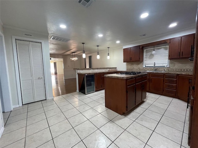 kitchen with a center island, sink, an inviting chandelier, crown molding, and pendant lighting