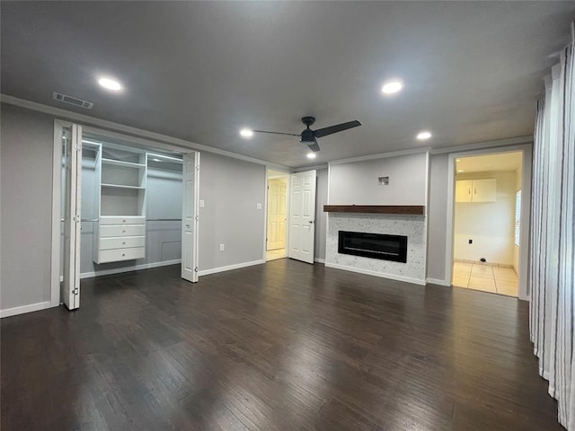 unfurnished living room with ceiling fan, dark hardwood / wood-style flooring, and ornamental molding