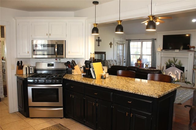 kitchen with hanging light fixtures, ceiling fan, light tile patterned floors, white cabinetry, and stainless steel appliances