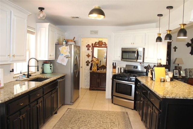 kitchen featuring sink, decorative light fixtures, light tile patterned flooring, white cabinetry, and stainless steel appliances