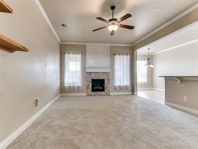 unfurnished living room with light carpet, ceiling fan with notable chandelier, a stone fireplace, and ornamental molding