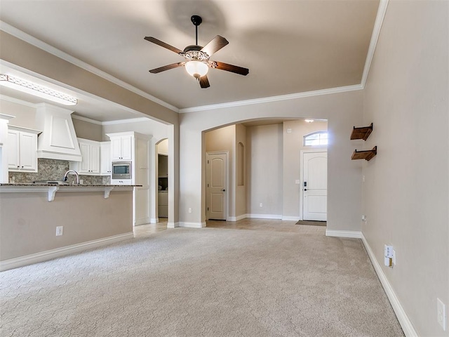 unfurnished living room featuring light carpet, crown molding, and ceiling fan