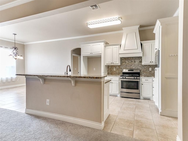 kitchen with white cabinets, stainless steel appliances, premium range hood, and a notable chandelier