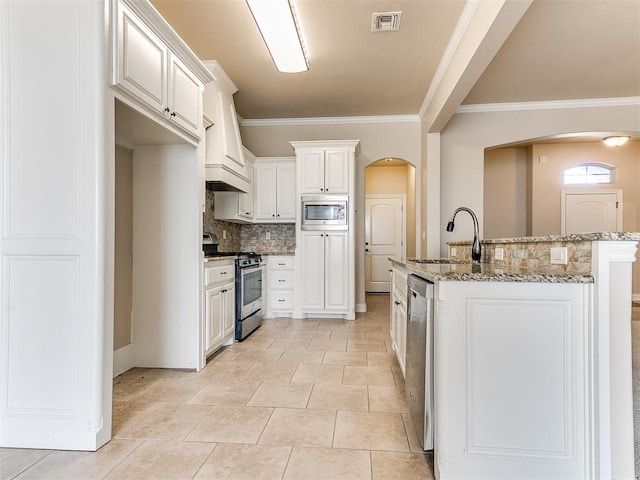 kitchen with crown molding, sink, appliances with stainless steel finishes, light stone counters, and white cabinetry