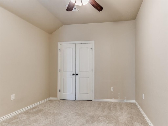 unfurnished bedroom with ceiling fan, a closet, light carpet, and vaulted ceiling