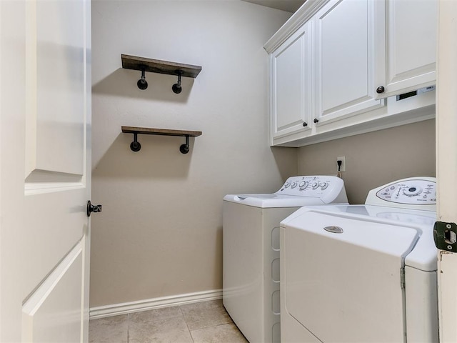 laundry room featuring cabinets, light tile patterned floors, and separate washer and dryer