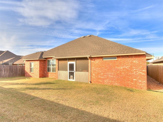 rear view of property with a sunroom and a lawn