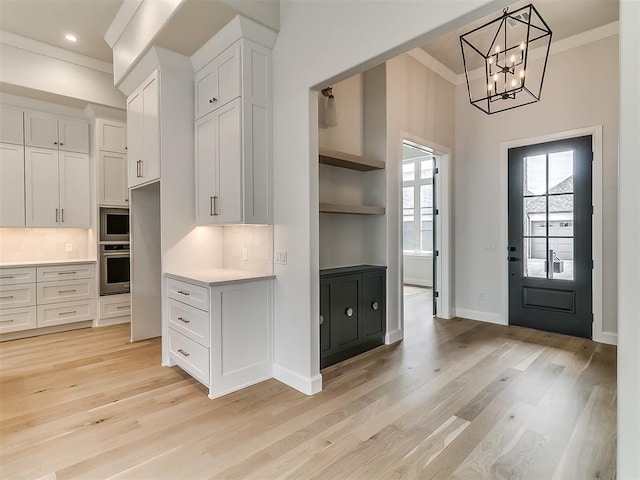 16413 Burgundy E Dr, Edmond, OK 73013 - kitchen with stainless steel appliances, light countertops, white cabinets, light wood finished floors, and crown molding