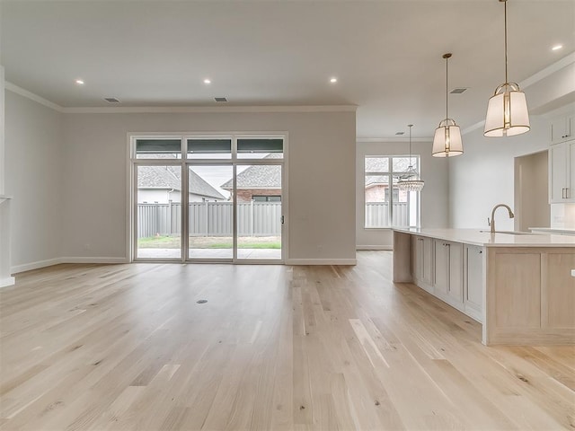 16413 Burgundy E Dr, Edmond, OK 73013 - unfurnished living room featuring crown molding, a sink, baseboards, light wood-type flooring, and recessed lighting