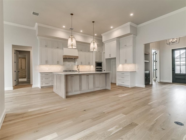 16413 Burgundy E Dr, Edmond, OK 73013 - kitchen with ornamental molding, appliances with stainless steel finishes, white cabinetry, backsplash, and a center island with sink