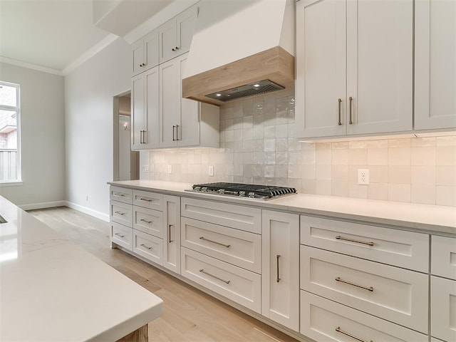 16413 Burgundy E Dr, Edmond, OK 73013 - kitchen featuring premium range hood, ornamental molding, stainless steel gas stovetop, light wood-style floors, and decorative backsplash