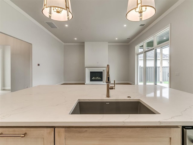 16413 Burgundy E Dr, Edmond, OK 73013 - kitchen featuring a sink, ornamental molding, open floor plan, a fireplace with raised hearth, and light stone countertops