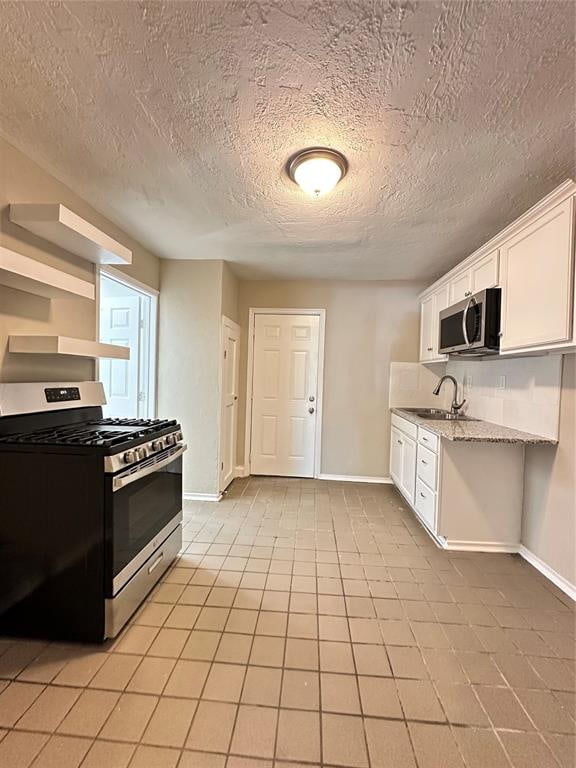 kitchen featuring light stone countertops, stainless steel appliances, white cabinets, a textured ceiling, and light tile patterned flooring