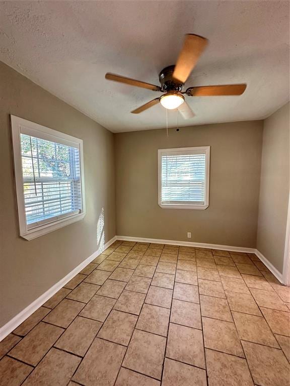 tiled empty room with a textured ceiling, a wealth of natural light, and ceiling fan