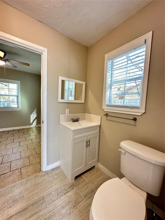 bathroom featuring vanity, ceiling fan, toilet, and a textured ceiling