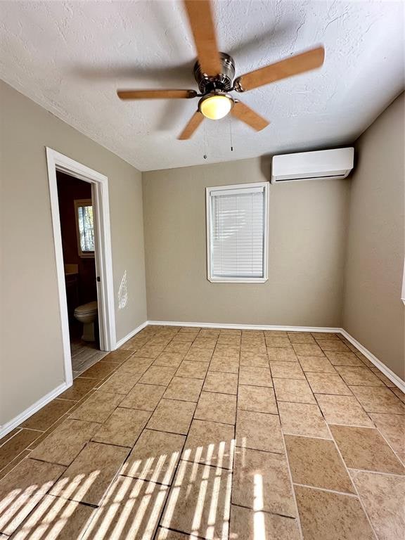 empty room featuring a wall mounted air conditioner, ceiling fan, and a textured ceiling