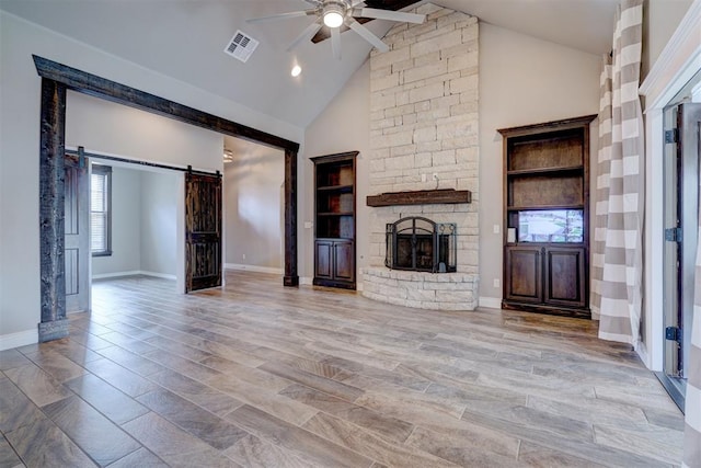 unfurnished living room featuring built in shelves, ceiling fan, high vaulted ceiling, light hardwood / wood-style flooring, and a stone fireplace