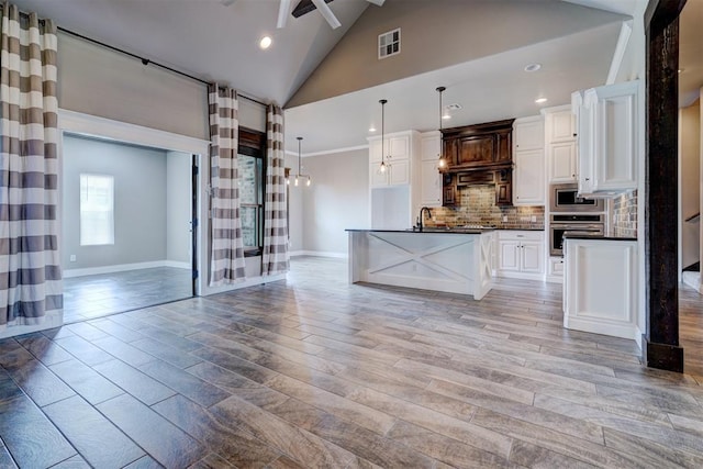 kitchen featuring appliances with stainless steel finishes, a center island with sink, light hardwood / wood-style flooring, and white cabinetry