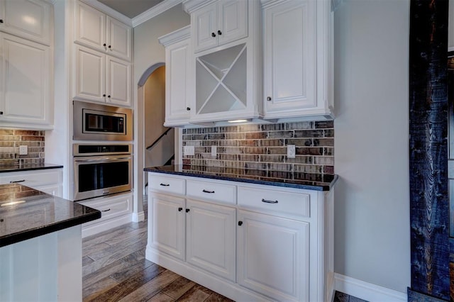 kitchen featuring decorative backsplash, appliances with stainless steel finishes, crown molding, wood-type flooring, and white cabinetry