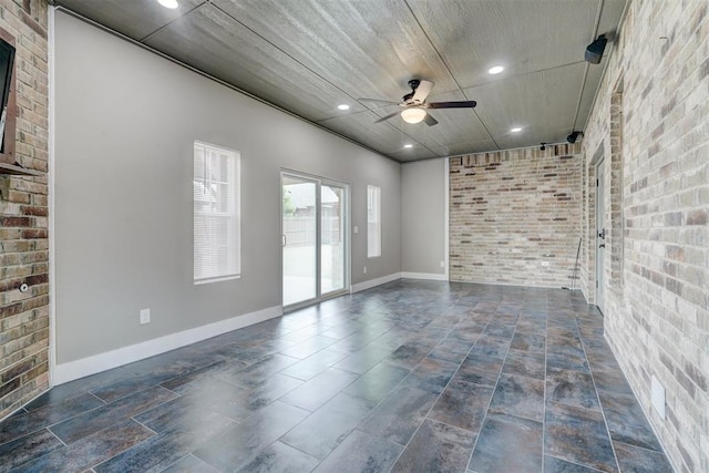 spare room with ceiling fan and brick wall