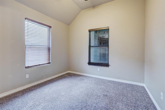 carpeted empty room with vaulted ceiling