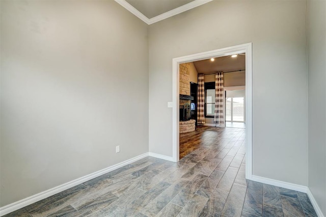 empty room featuring a stone fireplace and ornamental molding