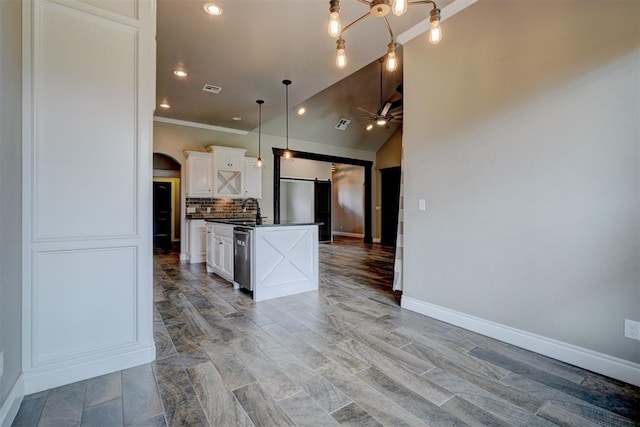 kitchen featuring appliances with stainless steel finishes, tasteful backsplash, a kitchen island with sink, a barn door, and white cabinets