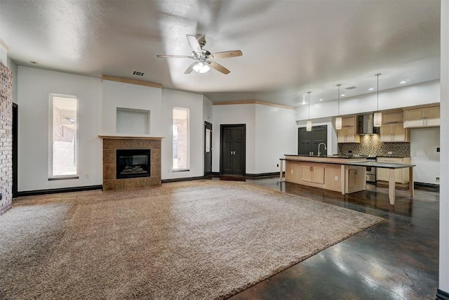 kitchen with a wealth of natural light, wall chimney range hood, tasteful backsplash, pendant lighting, and a center island with sink