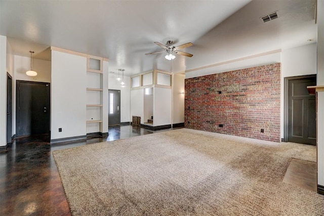 unfurnished living room with ceiling fan and brick wall