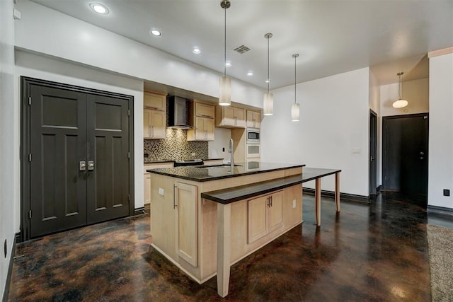 kitchen with a kitchen island with sink, wall chimney range hood, sink, tasteful backsplash, and decorative light fixtures