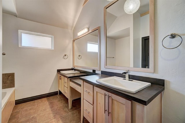 bathroom featuring a washtub, vanity, and vaulted ceiling