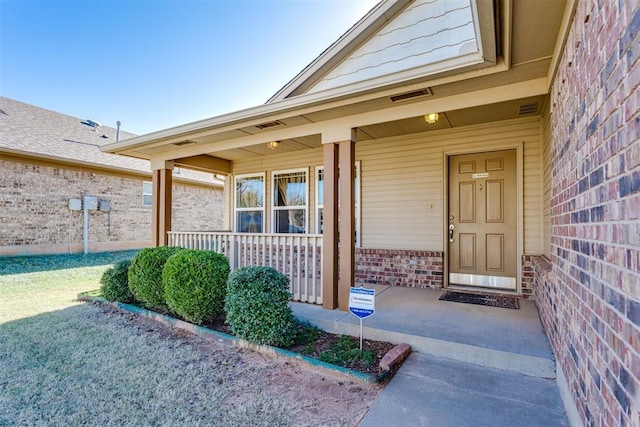 entrance to property with a porch and brick siding