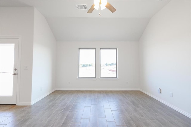 empty room featuring visible vents, baseboards, light wood-type flooring, a ceiling fan, and lofted ceiling