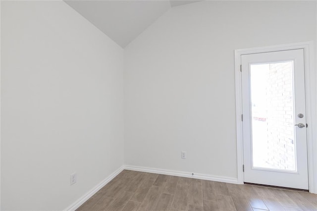 spare room with baseboards, vaulted ceiling, and wood finished floors