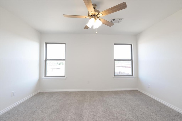 spare room with ceiling fan, visible vents, baseboards, and carpet floors